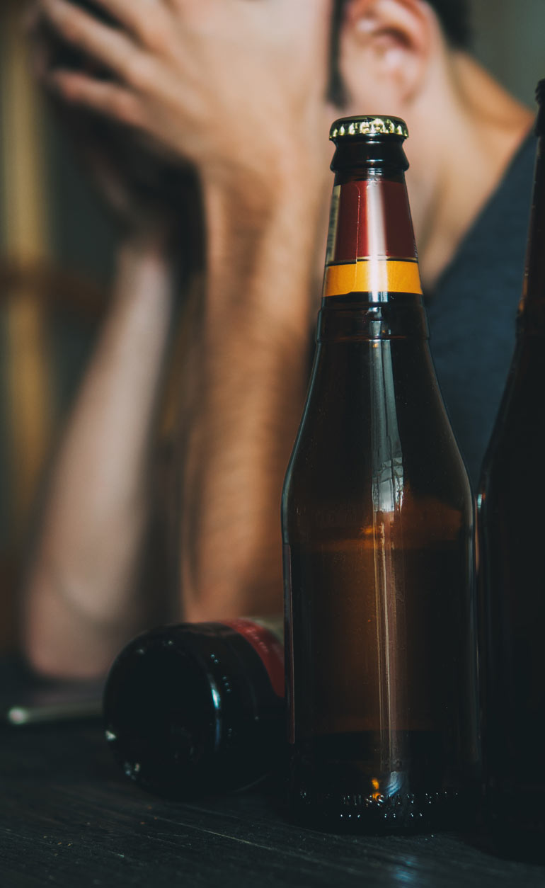 sad man with empty beer bottles nearby