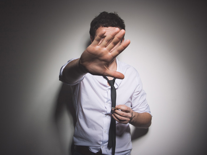 man holding up hand in 'go away' gesture