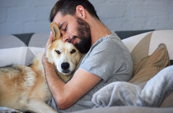 man hugging on his dog at home