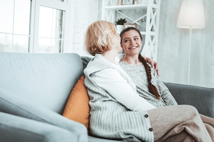 mom and daughter having talk on couch at home - drinking