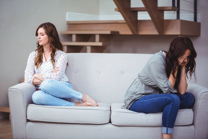 two young women sitting on opposite ends of a couch - toxic relationship