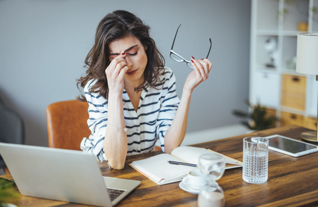 A woman looking stressed in front of a computer.
