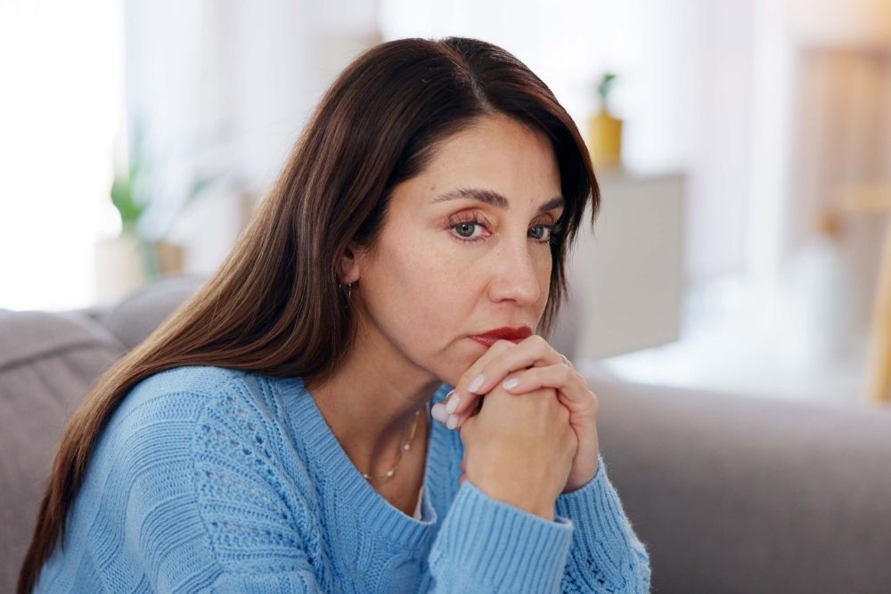 Safe Harbor - Understanding Relapse and How to Prevent It. A concerned woman sits on a couch staring into the distance. She rests her chin on her hands.